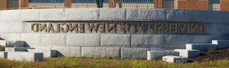 A metal sign against a brick wall reads "University of New England" 